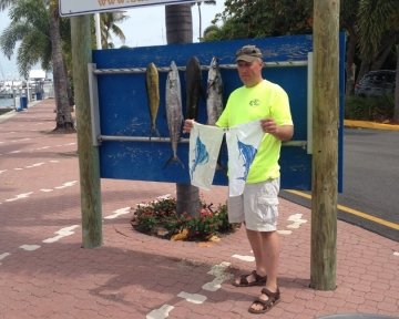 Guy holding up blue marlin flags in front of the sailfish marina sign